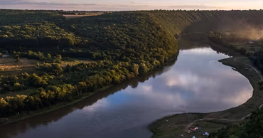Aerial view of the Dniester River winding through a forested landscape at sunset.