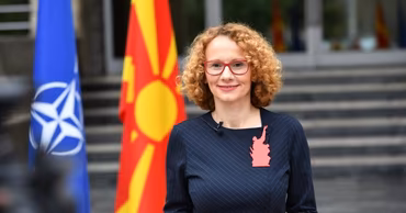 Radmila Shekerinska standing in front of NATO and North Macedonia flags.