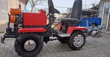 A red mini-tractor parked on a paved surface.