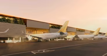 A view of an airport terminal with several airplanes parked on the tarmac at sunset.