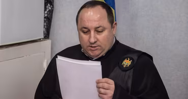 A Moldovan judge in a black judicial robe reading a document.