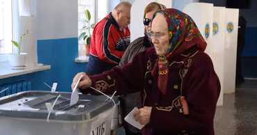 An elderly woman casting her ballot in a polling station in Moldova.