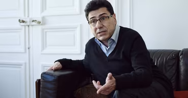 French economist Philippe Aghion sitting on a leather sofa.