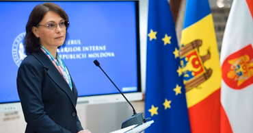 Daniela Misail-Nichitin speaking at a podium with Moldovan and EU flags in the background.