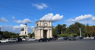 The Triumphal Arch and Metropolitan Cathedral in the center of Chisinau with traffic on the road.