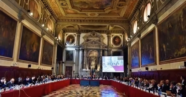 A wide shot of the Venice Commission meeting in a historic hall.