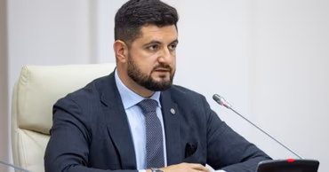Dorin Junghietu sitting at a conference table with a microphone.