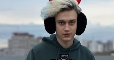 Nikolai Lebedev, known as Nekoglai, wearing a green hoodie and red devil horns.