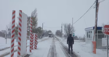 A snowy view of the Giurgiulesti border crossing point with a security officer standing nearby.