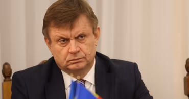 Valeriu Chiveri sitting at a table with a nameplate and a small flag.