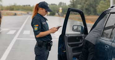 A Moldovan border police officer inspecting documents of a driver at a border crossing point.