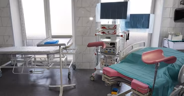 A modern hospital delivery room with medical equipment and a birthing bed.