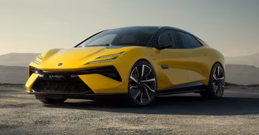 A yellow Lotus Emeya electric car parked on a gravel surface.