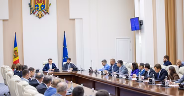 Moldovan government officials attending a formal meeting in a conference room with the national coat of arms.