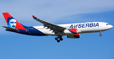 An Air Serbia passenger airplane in flight against a clear blue sky.