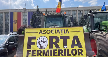 A tractor with a Forța Fermierilor banner parked in front of a government building in Moldova.