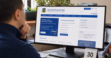 A person looking at the State Tax Service website on a computer monitor.