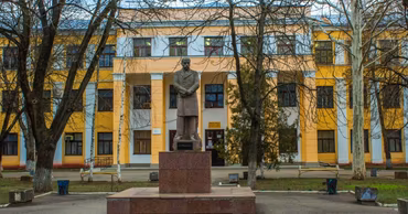 A Romanian-language school building in Transnistria with a statue of a poet in front.