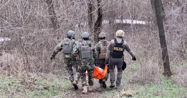 Moldovan police and military personnel carrying equipment in a wooded area near the crash site.