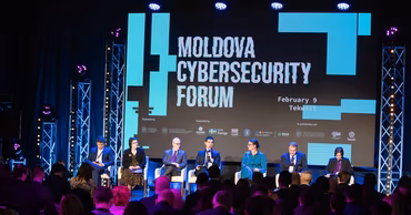 Panelists speaking at the Moldova Cybersecurity Forum in front of a large screen.